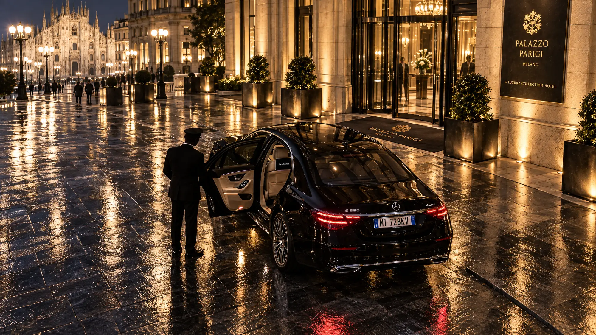 Autista che apre la portiera di una Mercedes Classe S davanti a un hotel di lusso a Milano, con il Duomo sullo sfondo